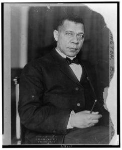 Seated three-quarter length portrait of Booker T. Washington with a writing implement in his right hand. 