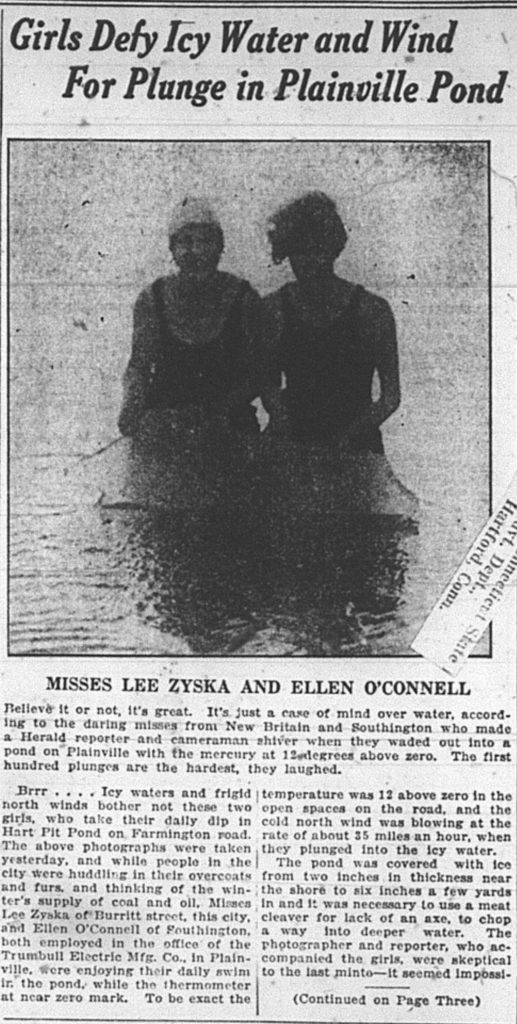 Image of two young women standing waist-deep in frigid water. 